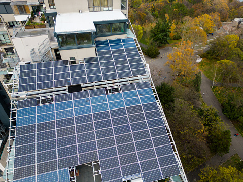Drone flight along the facade of a modern office or residential building with solar panels on the roof.