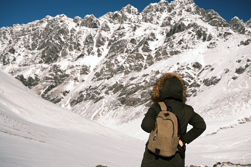 Female 46-year-old tourist is looking at view on mountain pass in winter (Chon-Ashuu pass, about 4000 m)