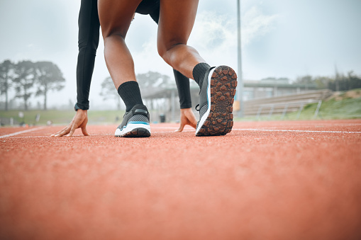 Woman, runner and start legs on race track for marathon practice, challenge or competition athlete. Black person, ready active in stadium for exercise strong achievement on field, test or training