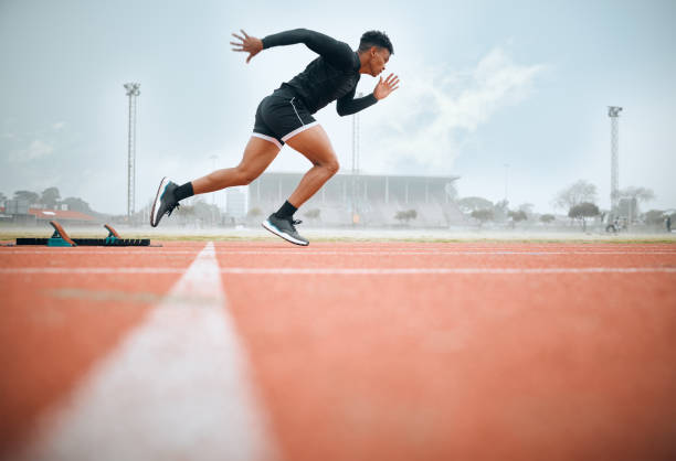 Man, athlete and ready for race on track with practice, training or exercise for competition. Black person, runner and fast with dedication, determination and passion on face with speed for sport Man, athlete and ready for race on track with practice, training or exercise for competition. Black person, runner and fast with dedication, determination and passion on face with speed for sport mens track stock pictures, royalty-free photos & images