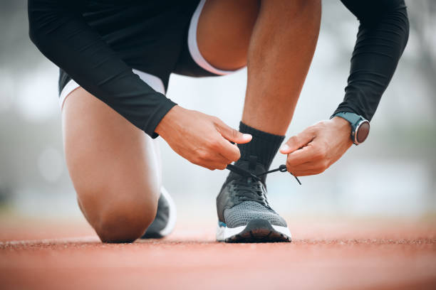 istock Running, track and runner tie shoes in stadium for marathon training, exercise and cardio workout. Fitness, sports and closeup of person tying sneaker laces for performance, race event and challenge 1834494012