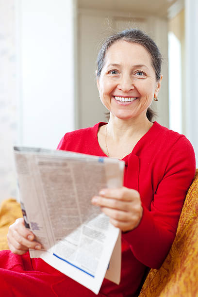 istock cheerful mature woman  with newspaper 183450277
