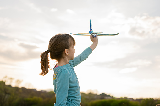 A happy girl plays with a toy airplane in nature during a spring day