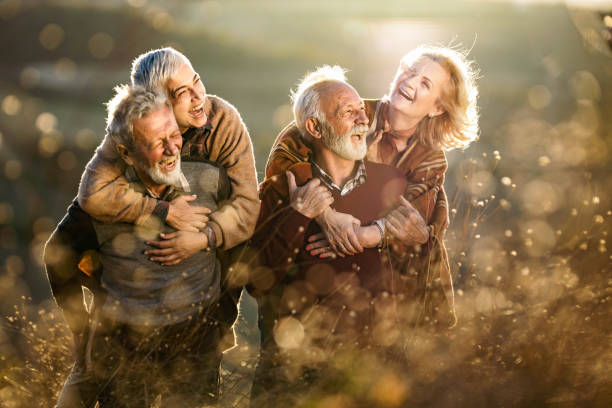 istock Happy mature couples having fun while piggybacking in autumn day. 1834545214