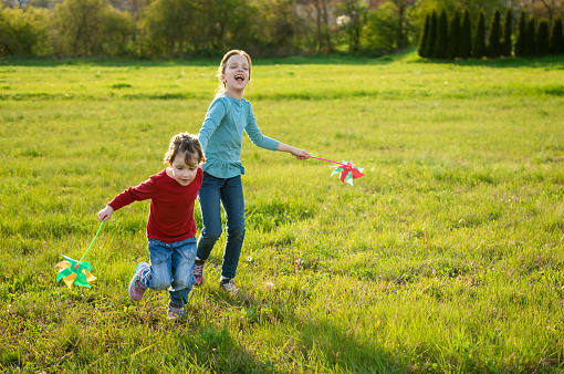Four little kids running in the park with kite happy and smiling
