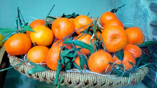 Greengrocer, heap of oranges in basket, green leaves. Fruit store . Farmer´s market.