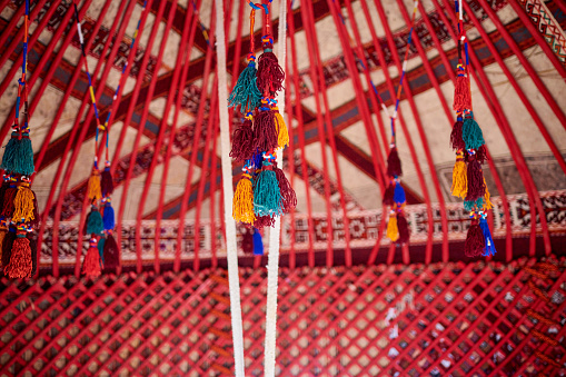 Traditional national elements, yurt decorations. Embroidery and patterns of nomads. A yurt is a portable circular tent, covered and insulated with hides or felt, and traditionally used as a dwelling by several distinct groups of nomadic peoples in the steppes and mountains of Central Asia.\nA yurt is a portable house, ideally suited to a nomadic lifestyle.