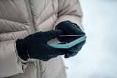 Smartphone with blank black screen in female hands. Winter shot, warm clothing. Communication, messaging and social network concept