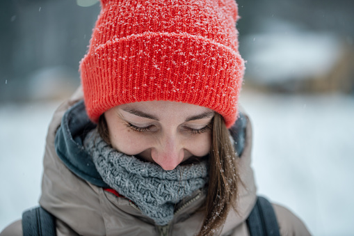 Cute and shy woman at snowing day, close-up portrait