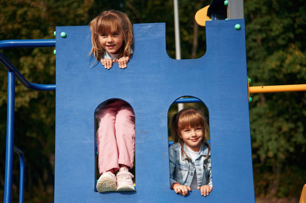 istock Hiding behind blue construction, smiling. Kids are having fun on the playground 1834631164