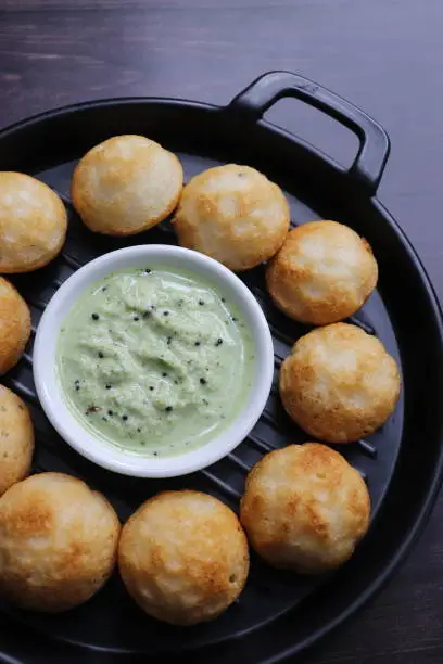 Photo of Paniyaram are savory balls made using fermented rice and urad dal batter along with tempered onion and spices. Also known as Paddu, Ponganalu, Kuli, bugga, and appe. served with coconut chutney