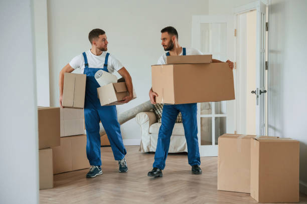 istock Boxes in hands. Two moving service employees in a room 1834676778