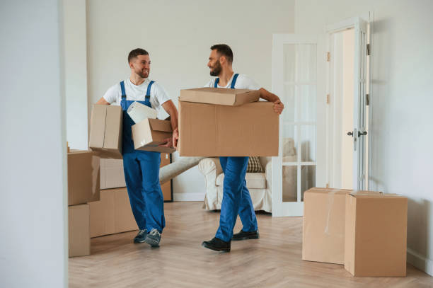 istock Boxes in hands. Two moving service employees in a room 1834676946