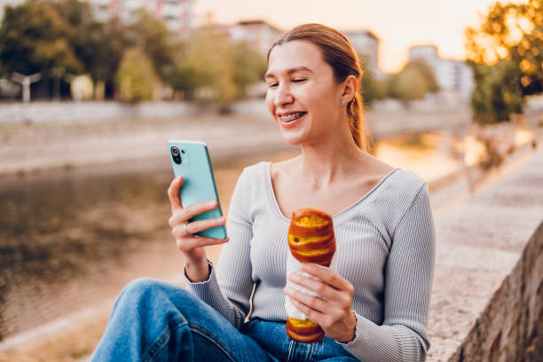 istock Woman eating pastry and using mobile phone 1834691958
