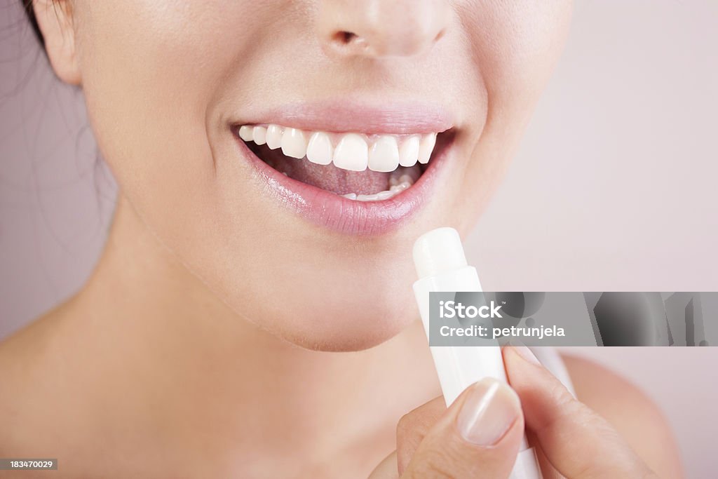 Lips care woman applying balsam on lips Lip Balm Stock Photo