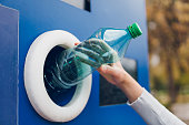 Young woman recycling plastic bottles in a machine