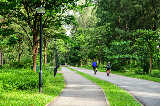 Singapore – August 19, 2022: A man and a woman cycling together along the cycling path at Changi Beach Park in Singapore.