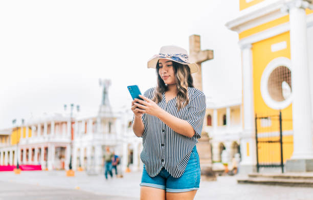 istock Female tourist texting phone in the square of Granada. Smiling young tourist in hat using cell phone on the street 1834733048