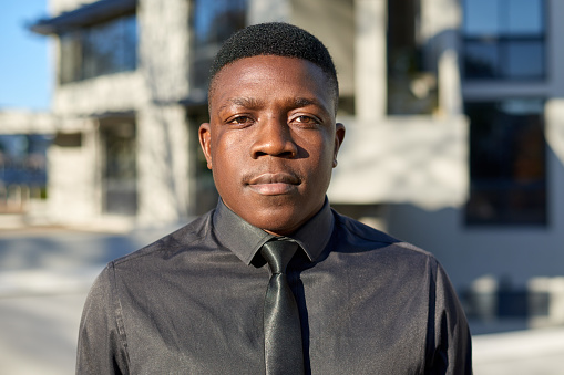 Portrait of young Black businessman, wearing black shirt and tie. High quality photo