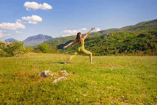 A moment of tranquility captured as a yoga instructor stretches and moves gracefully in a stunning green environment.