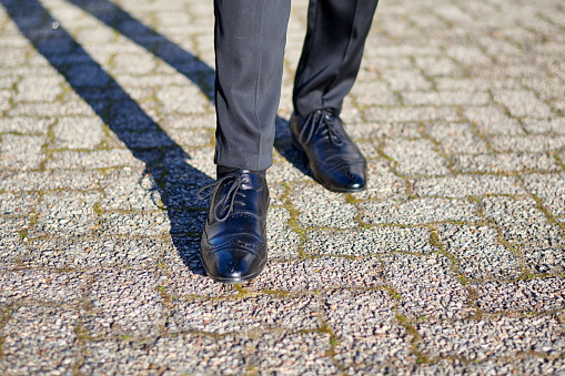 Close-up of man's shoes, dressed formally, standing on pavement. High quality photo