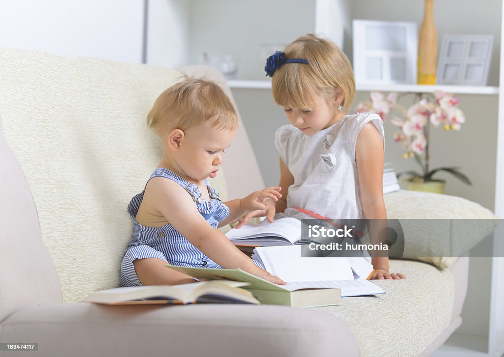 Kids with lot of books Little boy an girl sitting on the couch and reading books Baby - Human Age Stock Photo