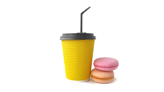 Coffee to go concept. Disposable yellow Cup of coffee or tea with delicious French macaroon cakes. Good morning.