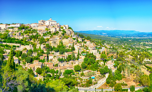 Vibrant color photography aerial view of french village, Ambronay city in Ain, Auvergne-Rhone-Alpes region France (Europe), in Bugey mountains in Alps. Summer season countryside with green meadow, field and trees nature and red roof from houses and buildings from the town, with famous abbey and church made of stone.