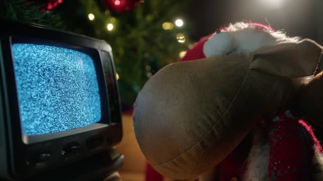 Puppet hypnotized by the white noise of an old tv