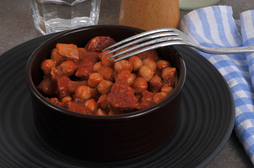 Chickpeas with chorizo served in a ramekin with a fork close-up