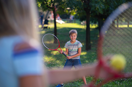 Happy boy playing tennis game whit his mother in the park