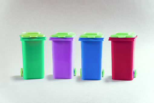 Multicolored toy plastic bins for different waste types, separate garbage collection concept