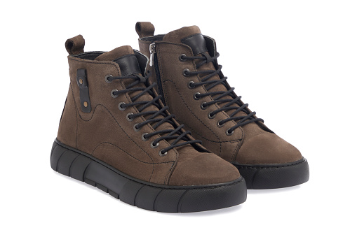 Black boots made of genuine leather. Men's winter shoes with laces, fashionable style. On a straw background, burlap.