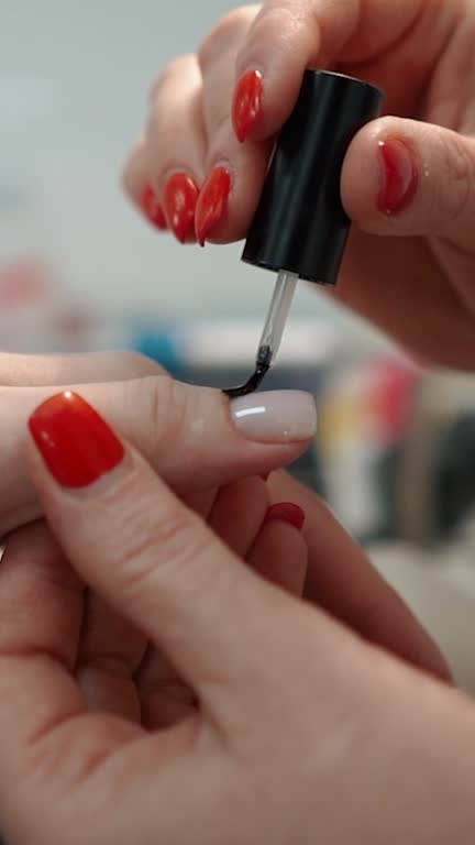 Beauty manicurist doing nails to a female client in a beauty salon, hands close-up