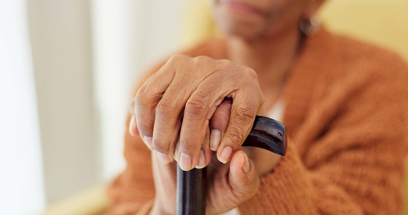 Hands, walking stick and senior woman with a disability, dementia or Alzheimer in a nursing home for senior care. Crutch, balance and old lady with osteoarthritis, Parkinson or osteoporosis or stroke