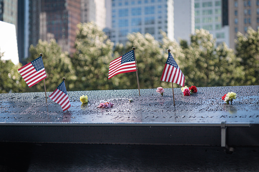 NEW YORK, USA-JULY 29, 2023: National September 11 Memorial, american flag, flowers, names, New York, USA