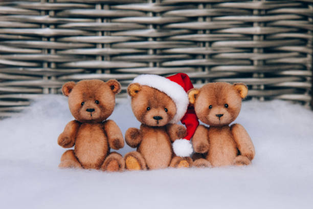Three funny and cute hand made toy bear with Christmas Santa hat on snowy background