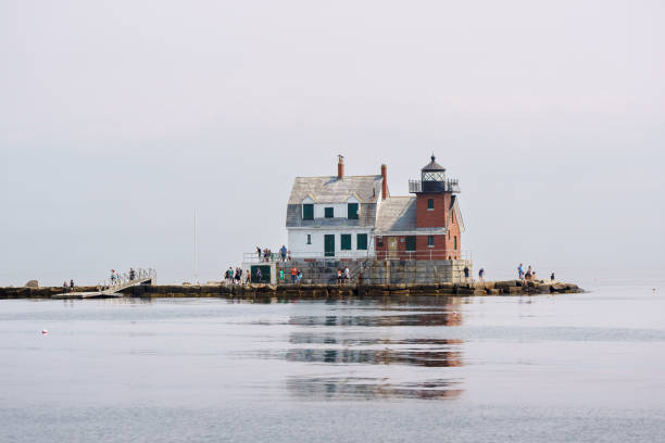 View of the Rockland Breakwater Lighthouse in the morning as fog lifts and sun begins to paint the lighthouse. Taken from the J & E Riggin schooner as we sail by.