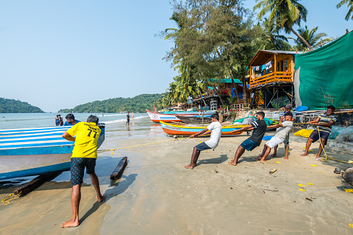 palolem, india. 2nd november, 2023: indians pushing a boat into the sand at palolem beach