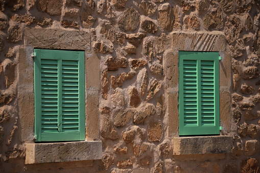 green bright window shutters of a stone house