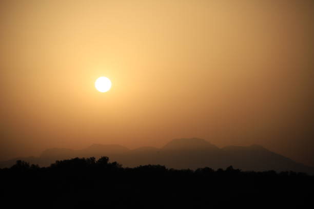 istock setting sun over mountain silhouette with Sahara desert dust in the air 1834886609