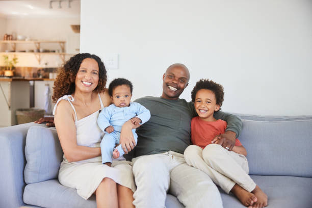 istock Smiling parents sitting with their two young sons on a sofa at home 1834901212