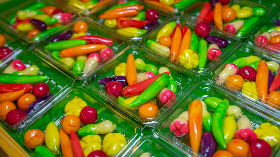 Thai dessert made from beans Molded into different shapes, glossy surface, various colors, mixed together in a clear plastic box. On the green artificial grass Suitable for use as a background image