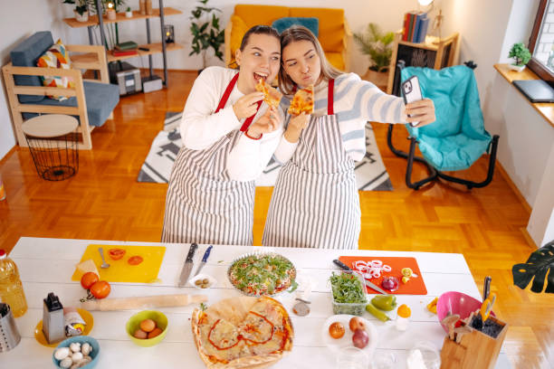 istock Girls having fun with making pizza at home and using mobile phone while in the kitchen 1834912040