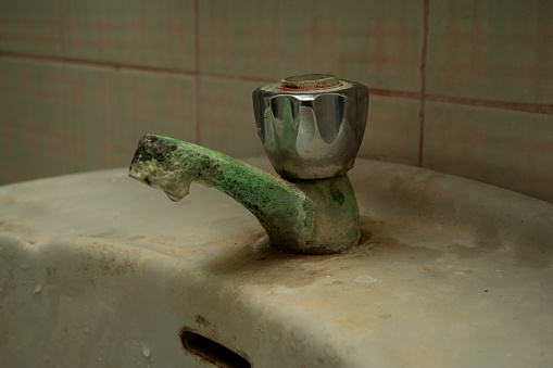 limestone accumulated faucet or water tab, efflorescence stain on old and dirty water tap on the sink in toilet