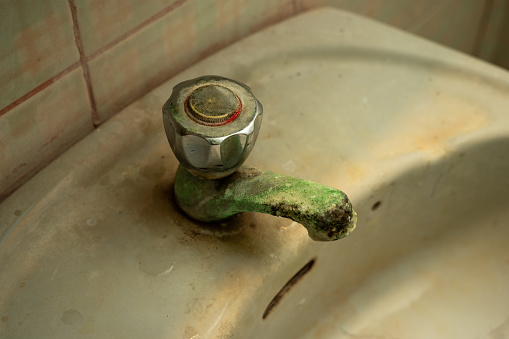 limestone accumulated faucet or water tab, efflorescence stain on old and dirty water tap on the sink in toilet