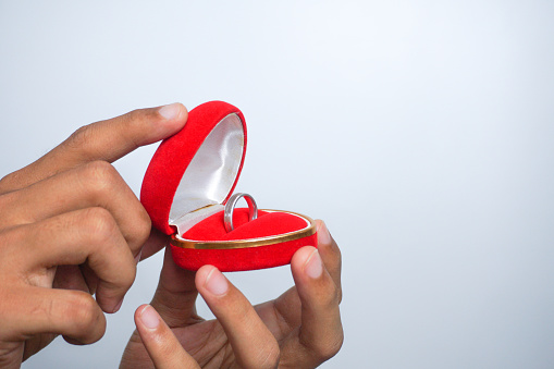 Gift with a ring in his hands. Giving a ring for Valentine's Day. Valentine's Day. Wedding ring in a red box