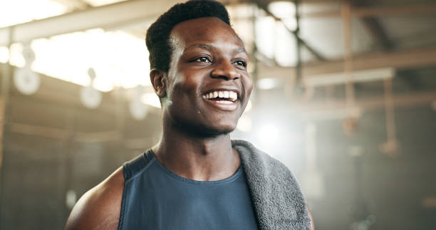 sonrisa, aptitud y cara de hombre negro en un gimnasio para entrenamiento, ejercicio y rutina de atletismo. entrenador personal masculino africano y con mentalidad feliz en un estudio deportivo para el entrenamiento, el progreso y el desafío corporal - male towel men human face fotografías e imágenes de stock