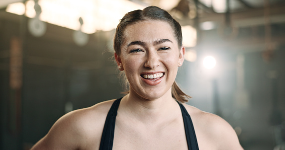 Laughing, fitness and face of happy woman at a gym for training, exercise and athletics routine. Smile, portrait and female personal trainer at sports studio for workout, progress and body challenge