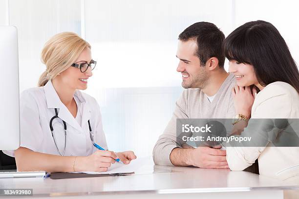 Smiling Doctor With Stethoscope Talking To Smiling Couple Stock Photo - Download Image Now